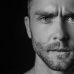 A close up of a man making a serious face in black and white.